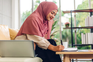 Young smiling beautiful muslim woman relaxing using laptop computer working and video conference meeting at home.work from home concept