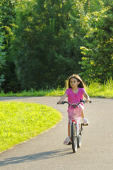 Fototapeta premium Young girl riding her bicycle down a curving rural road