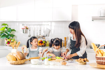 Portrait of enjoy happy love asian family mother and little toddler asian girl daughter child having fun cooking together with dough for homemade bake cookie and cake ingredient on table in kitchen