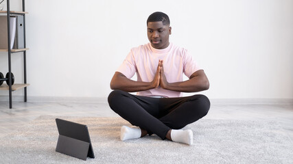 Home yoga. Calm black man. Online practice lesson. Harmony balance. Smiling african guy sitting...