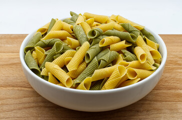 Fresh raw colored pasta. Italian Maccheroni al pettine on wooden table.