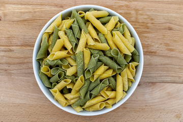 Fresh raw colored pasta. Italian Maccheroni al pettine on wooden table. View from above