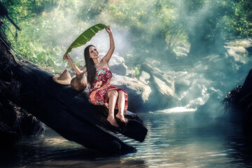 Village woman hold banana leaves to bathe in a spa in a countryside waterfall.Asian woman in nature relaxation waterfall background