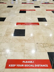 Red lines with social distance precaution in English on tiled floor at airport Antalya, Turkey. New normal travel after Covid-19 pandemic