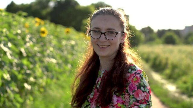 portrait of a smiling young girl with glasses, a blurred background of a field of sunflowers