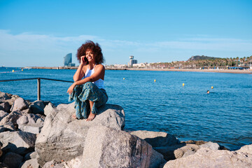 a curvy black afro woman using smartphone at Barcelona beach
