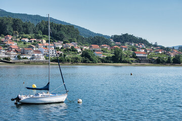 Obraz premium Barco velero fondeado en el estuario de la ría de Pontevedra junto a la villa de Combarro, España