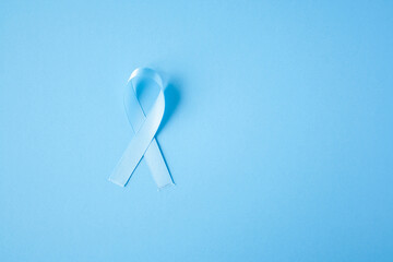 Prostate cancer awareness blue ribbon on blue background. Men healthcare concept, men carcinoma symbol.