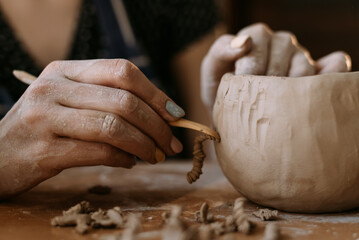 A sculptor makes a plate from a cast. woman potter working with clay brush hands close-up. applies...