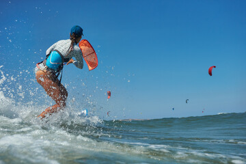 Kite surfer woman jumps with kiteboard  in transition and throws up the board - obrazy, fototapety, plakaty