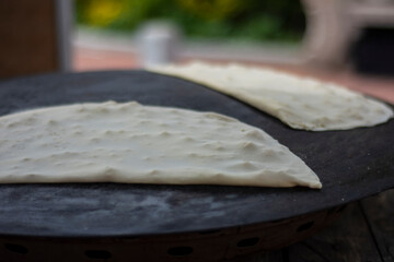 traditional turkish cuisine, street food: pancake. she prepares pancakes with traditional methods, on the floor table and with a rolling pin.