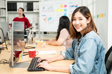 Obraz premium Beautiful asian woman working on computer at workplace. She looked straight at the camera and showed confidence.