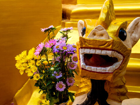 A bouquet of flowers for worship and a Burmese art lion statue at the base of the pagoda