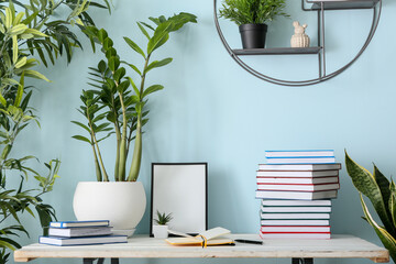 Table with books, frame and houseplants near color wall © Pixel-Shot