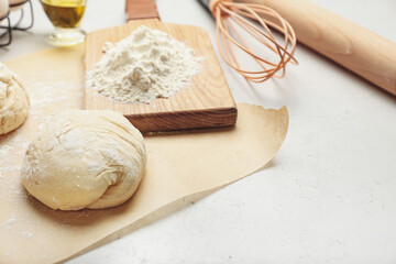 Fresh dough with ingredients for preparing bakery and utensils on light background