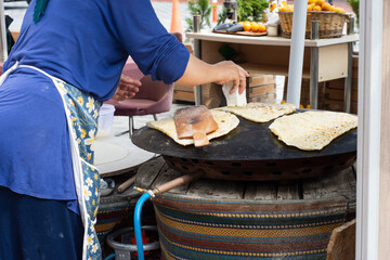 traditional turkish cuisine, street food: pancake. local woman cooks on metal sheet, in which she puts cheese, spinach, or potatoes. Selective Focus .