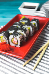 Tasty and fresh sushi set served in a red plate with wooden chopsticks. Close-up, selective focus on sushi.