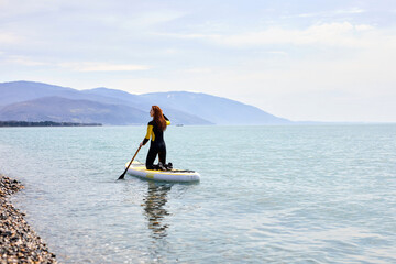 View from back on redhead Young woman sailing on beautiful calm sea with crystal clear water. The concept of summer holidays vacation travel, relax, active and healthy life in harmony with nature.