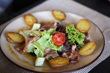 salad with potatoes beef and vegetables in a plate is on the table
