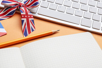 Stationery, keyboard and ribbon in colors of UK flag on orange background. Concept of learning English