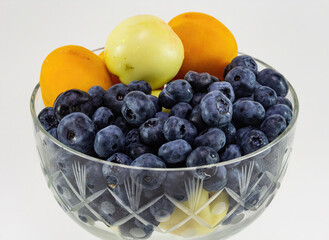 Still life with nectarines and apricots and blueberries on a white background.