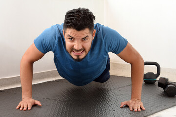 Obraz premium Caucasian athlete man doing push-ups. fitness at home young handsome man in sportswear doing push-ups. doing pectoral exercises