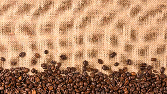 Roasted coffee beans on burlap background. Frame with coffee beans.