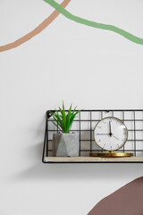 Shelf with alarm clock and decor hanging on color wall