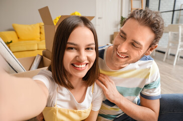 Young couple taking selfie in room on moving day