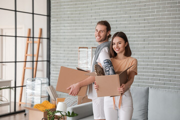 Fototapeta na wymiar Young couple with cardboard boxes in their new house on moving day
