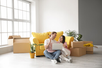 Young couple using laptop in their new house on moving day