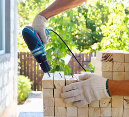 Master cabinetmaker makes wooden furniture with drill, nails, hammer. Handmade in home workshop.