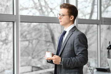 Young man drinking coffee near window