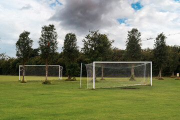 Two white soccer of football goal post on a grass field of a training ground.