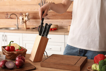 Man with knives and vegetables in kitchen