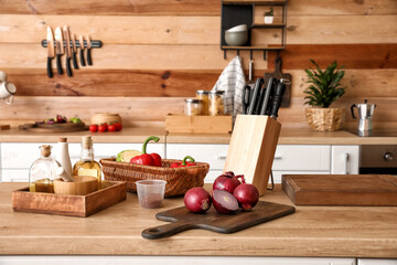 Stand with set of knives and vegetables on table in kitchen
