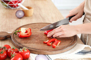 Obraz na płótnie Canvas Woman cutting bell pepper in kitchen, closeup