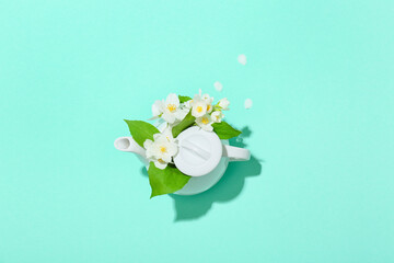 Composition with teapot and beautiful jasmine flowers on color background