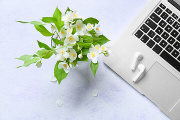 Modern laptop, earphones and beautiful jasmine flowers on light background