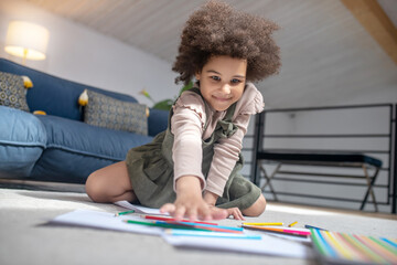 Little girl choosing colored pencil on floor