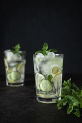 Detox Sassy Water. Cool and fresh drink with lemon, cucumber, mint, ginger and ice. Two glasses of lemonade on a black background