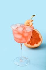 Glass of Hemingway daiquiri cocktail and grapefruit on color background