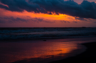 Naklejka na ściany i meble Beautiful sunset at Paradise island Sri Lanka, Bright vivid orange skyline, and the reflection on the beach waves creating perfect balance and harmony.
