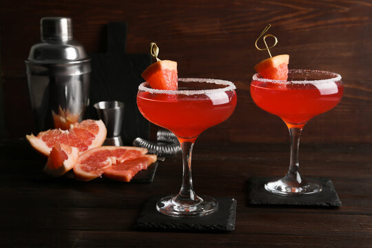 Glasses of Hemingway daiquiri cocktail, shaker and grapefruit on wooden background