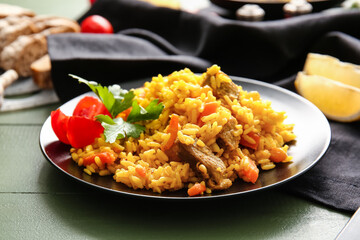 Plate with tasty pilaf on color wooden background