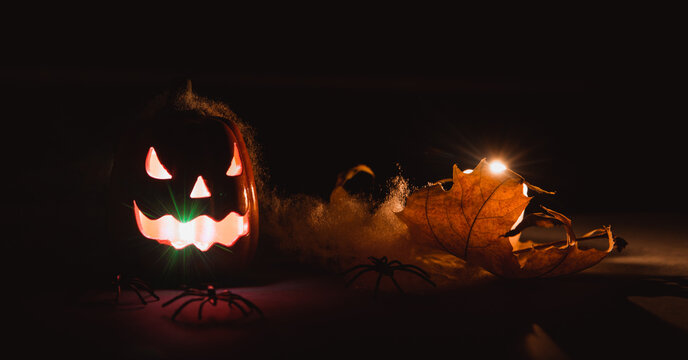 Halloween pumpkins smile and scrary eyes for party night. Close up view of scary Halloween pumpkin with eyes glowing inside and candle at black background