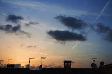 Beautiful Sunset with Silhouette of the rural town. Colorful sky, clouds and chemtrails.