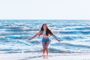 Young woman playing in the sea.woman make in sea water splash.Cheerful young woman having fun on the summer beach.