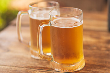 Two beer mugs closeup on wooden natural table.Two glass beer on wood background.
