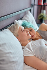 Happy cute beautiful caucasian women lesbian couple lover lying on bed in the morning with smiling face. Concept of gender LGBT sexuality with happy lifestyle together. Side view, copy space